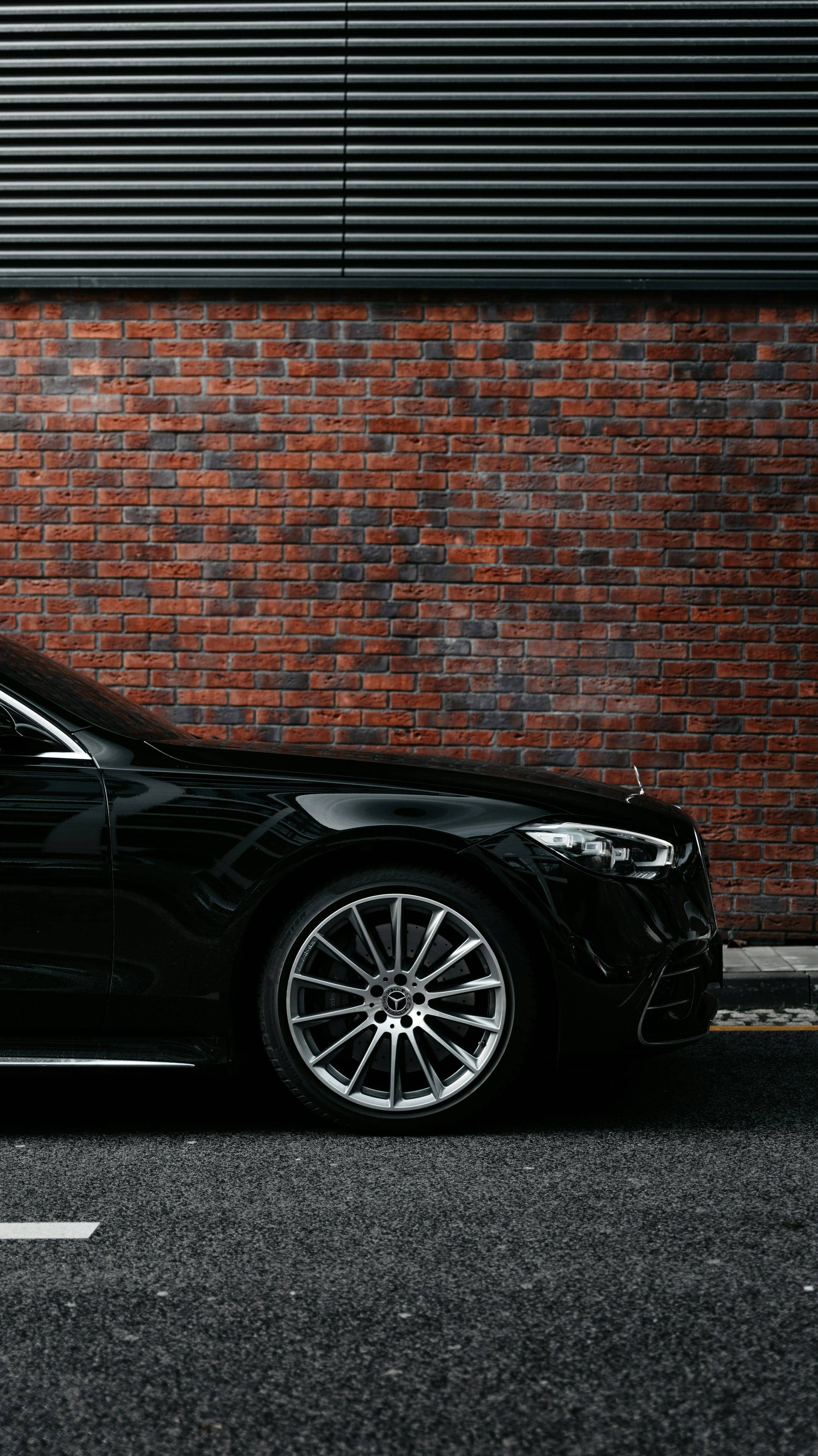 Črn Mercedes-Benz S-Class, sprednji del ob opečnati steni